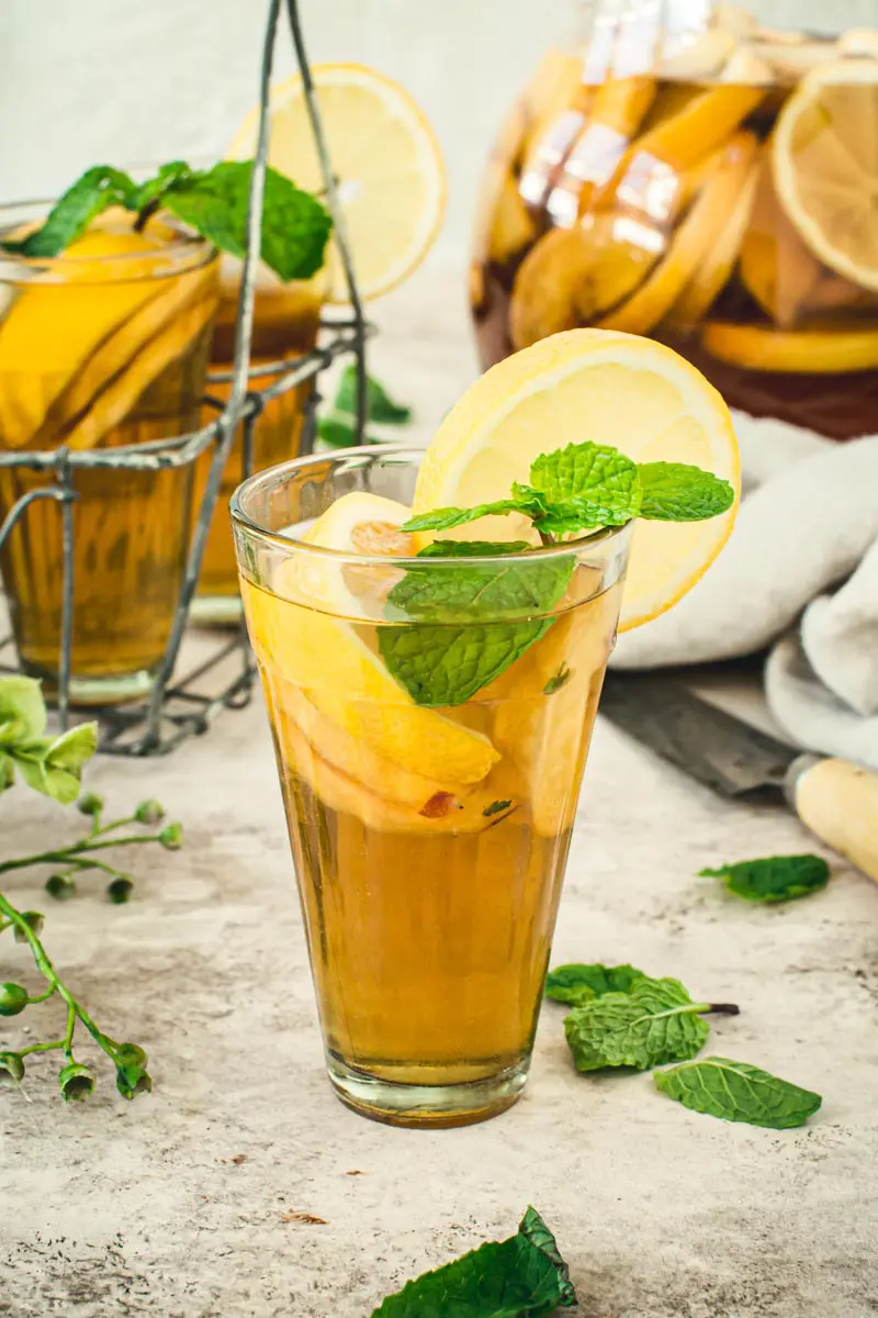 Lemon and mint topped over sangria iced tea in a glass.