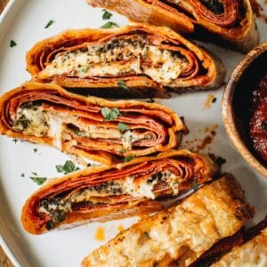 Italian Stromboli slices covered in fresh parsley on a white round plate.