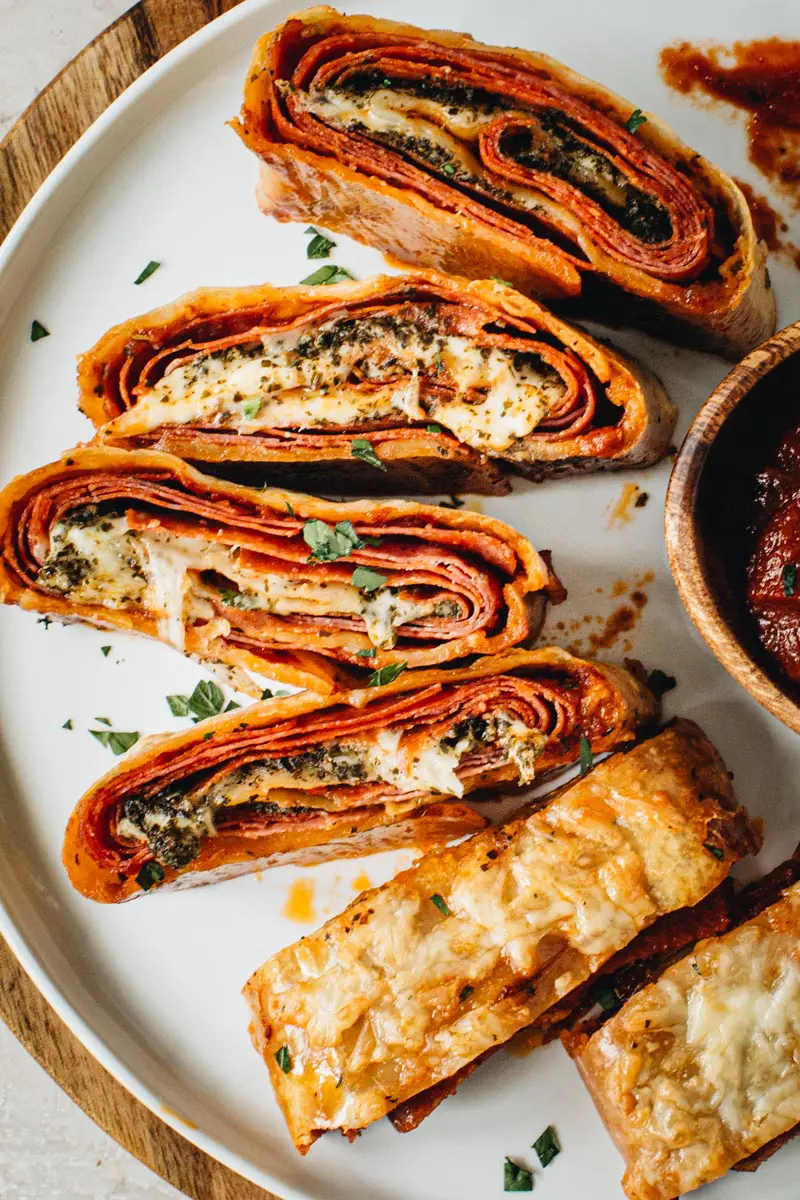 Italian Stromboli slices covered in fresh parsley on a white round plate.