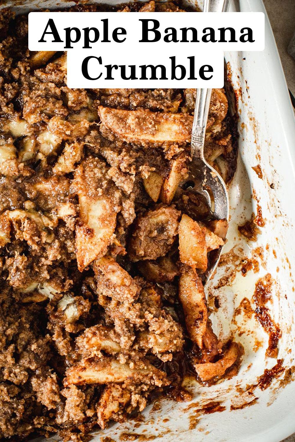 Apple banana crumble in a baking dish with a silver serving spoon.