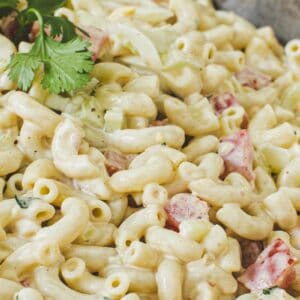 Southern macaroni salad with tomatoes and fresh parsley in a bowl.