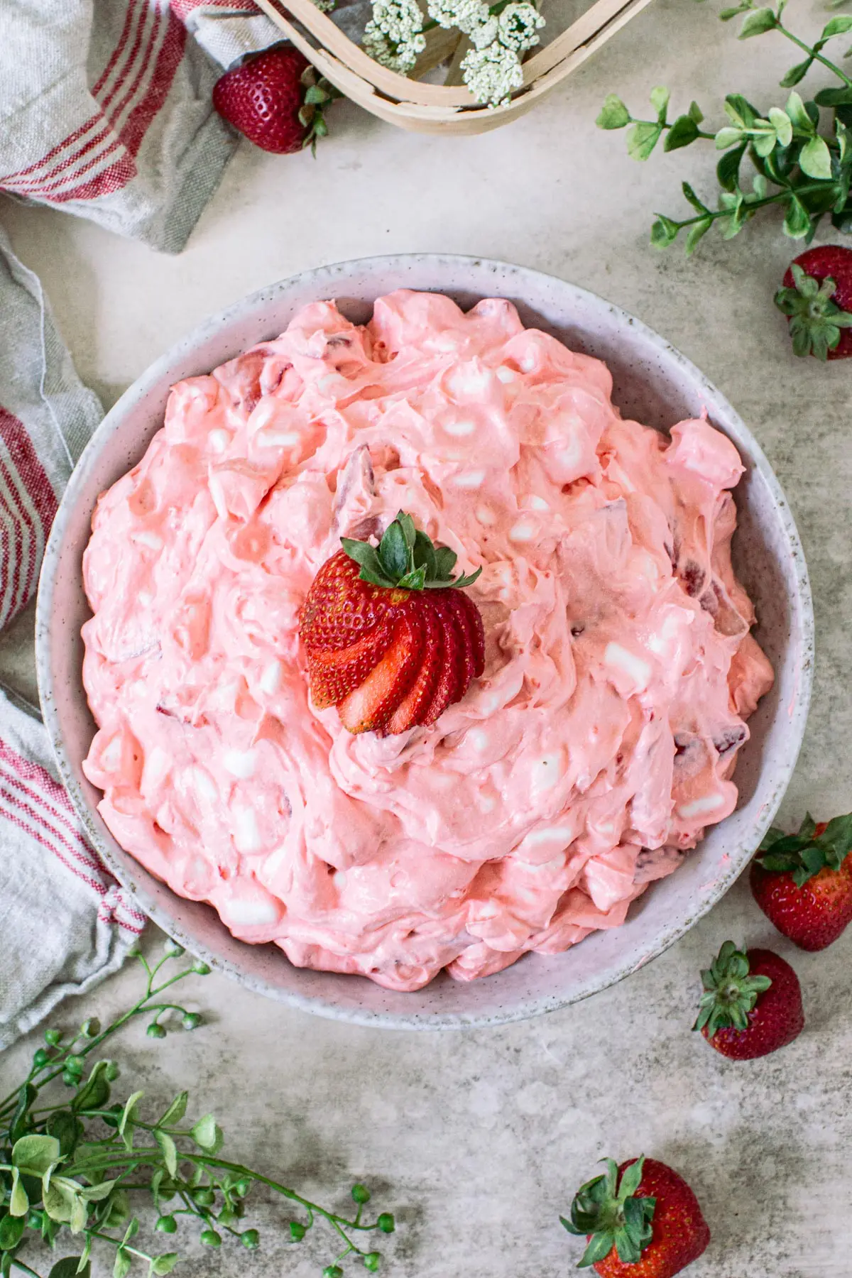 Strawberry jello fluff salad topped with a strawberry.