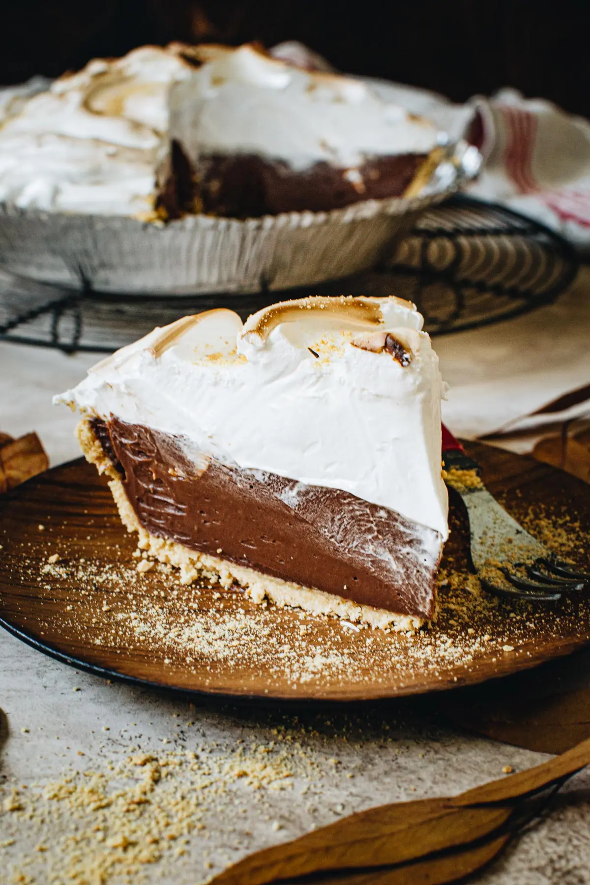 Slice of no-bake s'mores pie on a wooden plate.