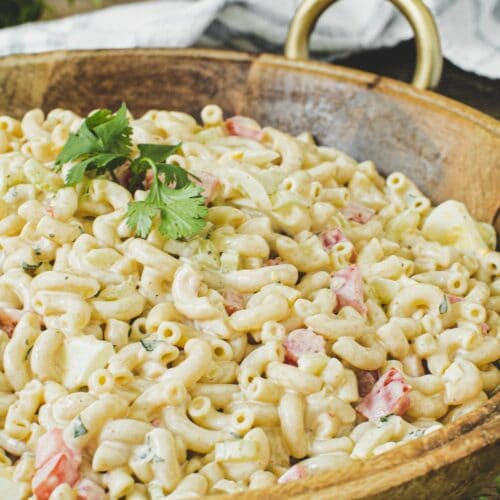 Southern macaroni salad in a wooden bowl topped with fresh parsley.