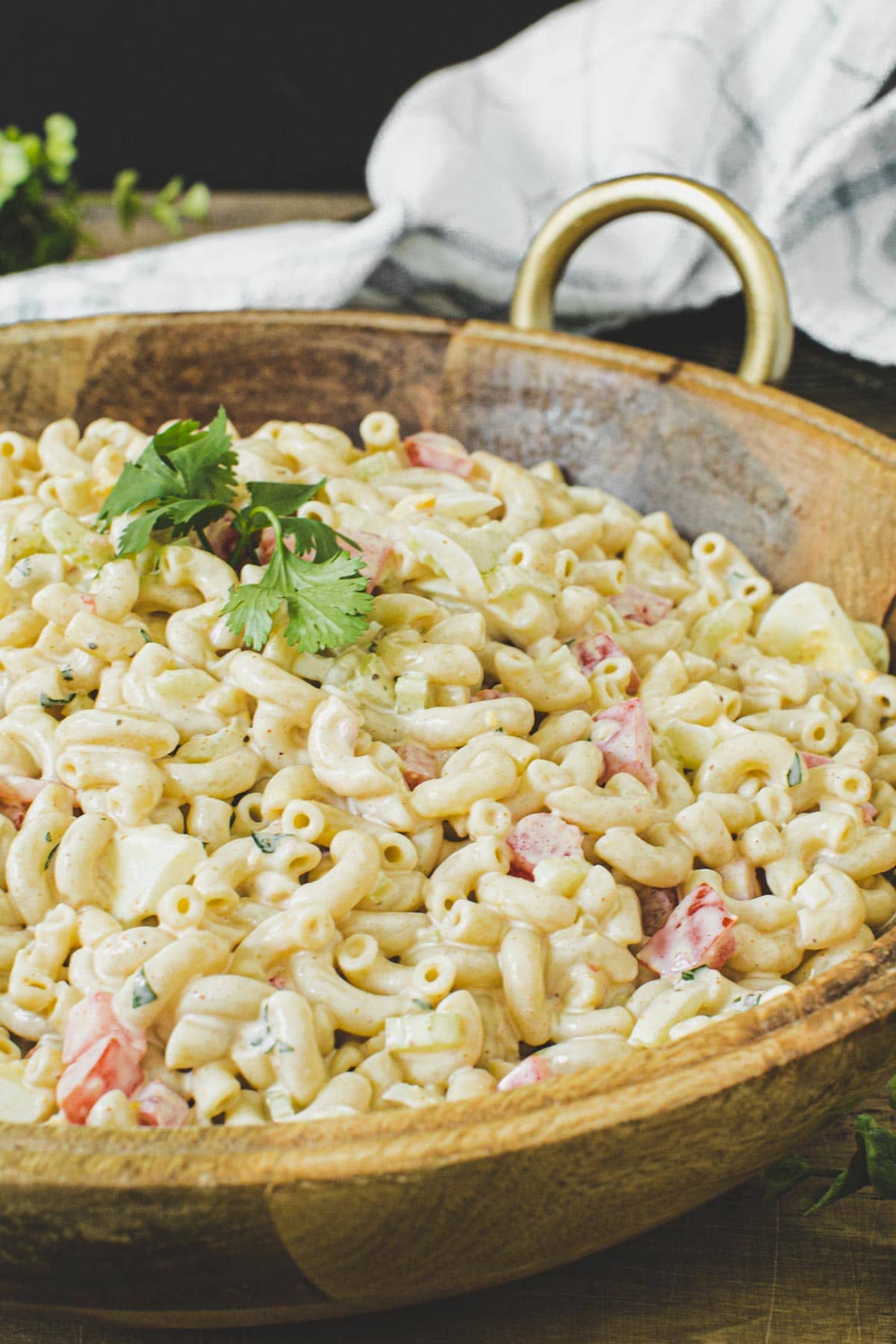 Southern macaroni salad in a wooden bowl topped with fresh parsley.