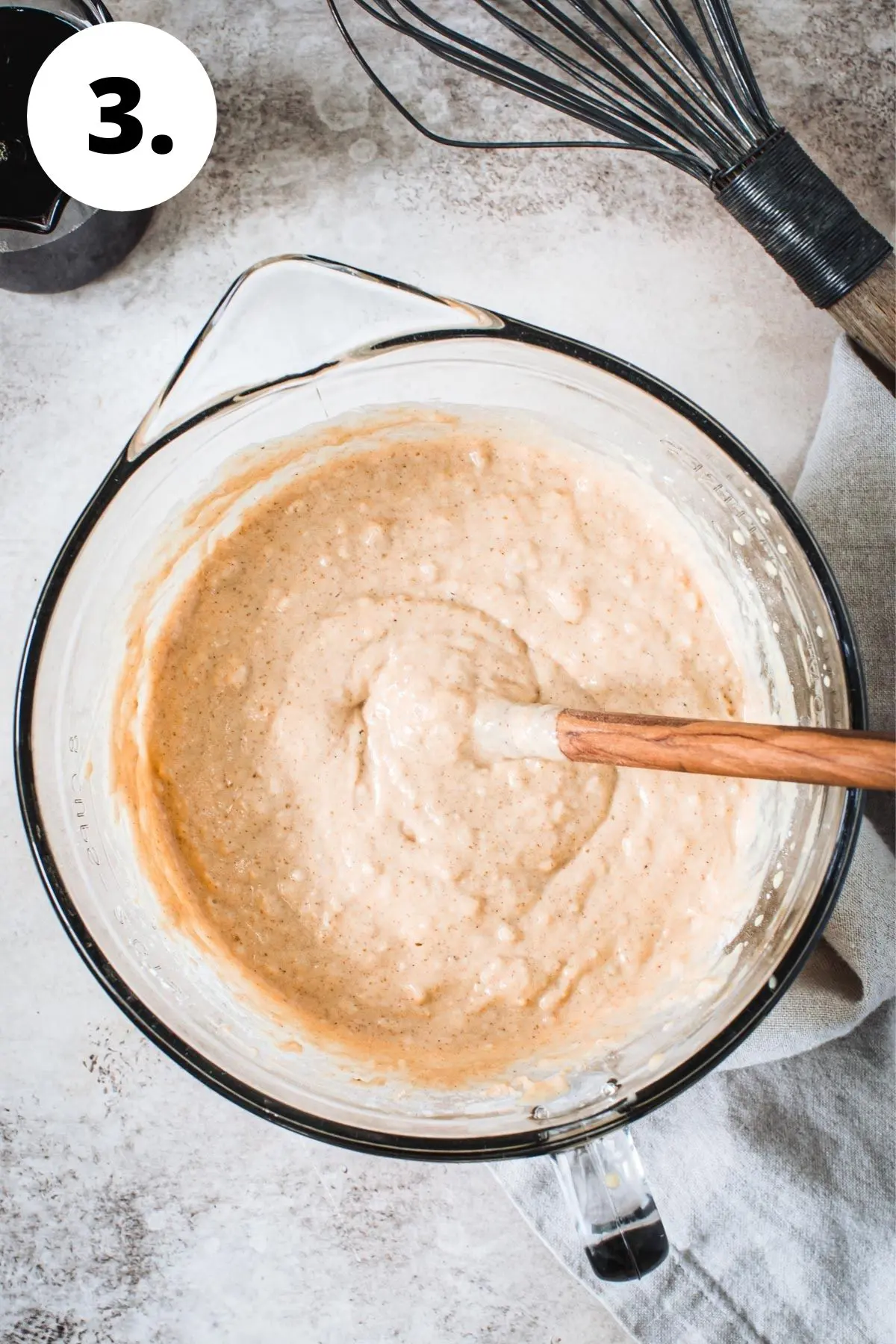 Sweet potato pancake batter in a mixing bowl with a wooden spoon.