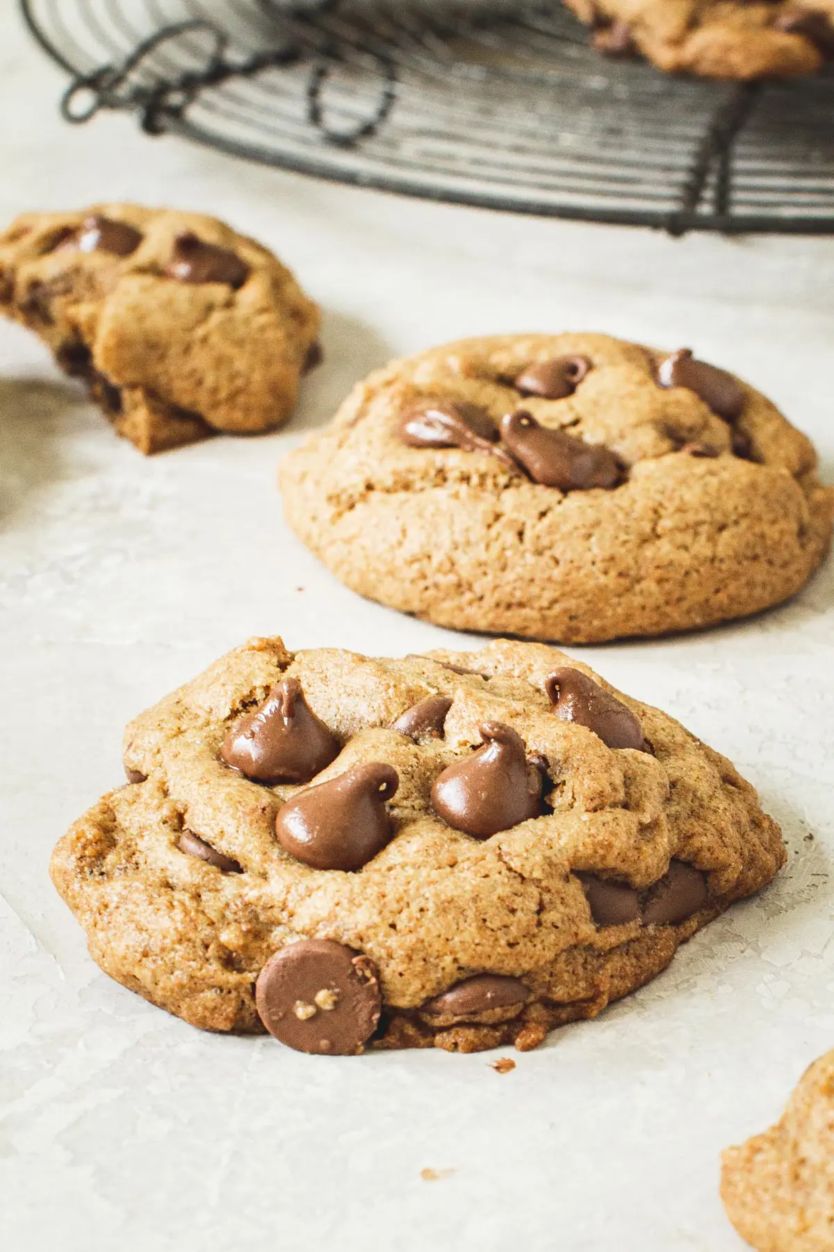 Whole wheat chocolate chip cookies with a round wire rack in the background.