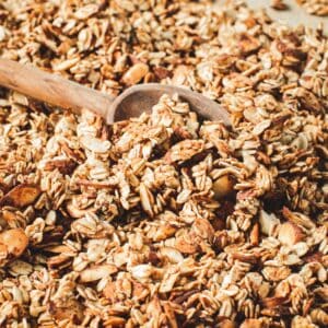 Honey vanilla granola with a wooden spoon scooping it up.