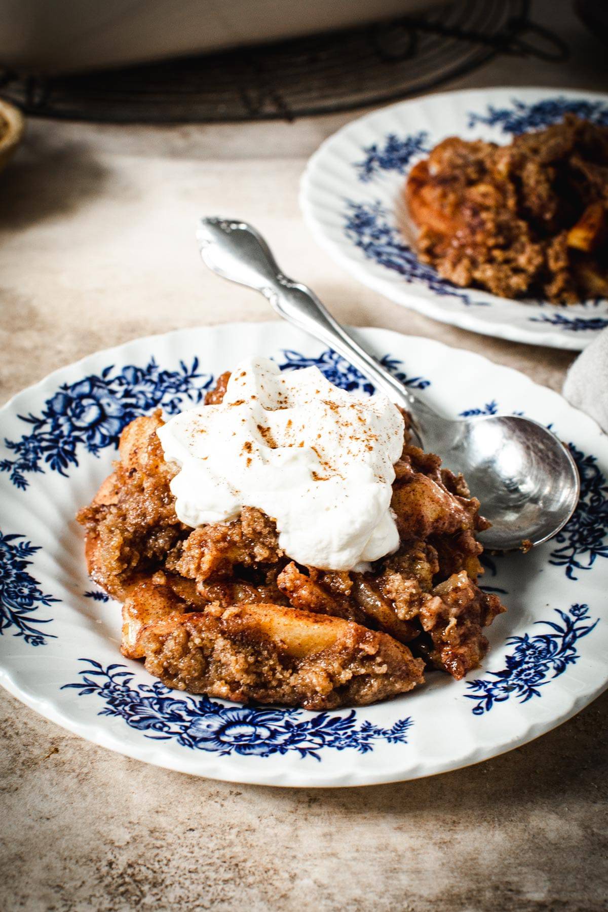 Baked apple crumble without oats topped with whipped cream.