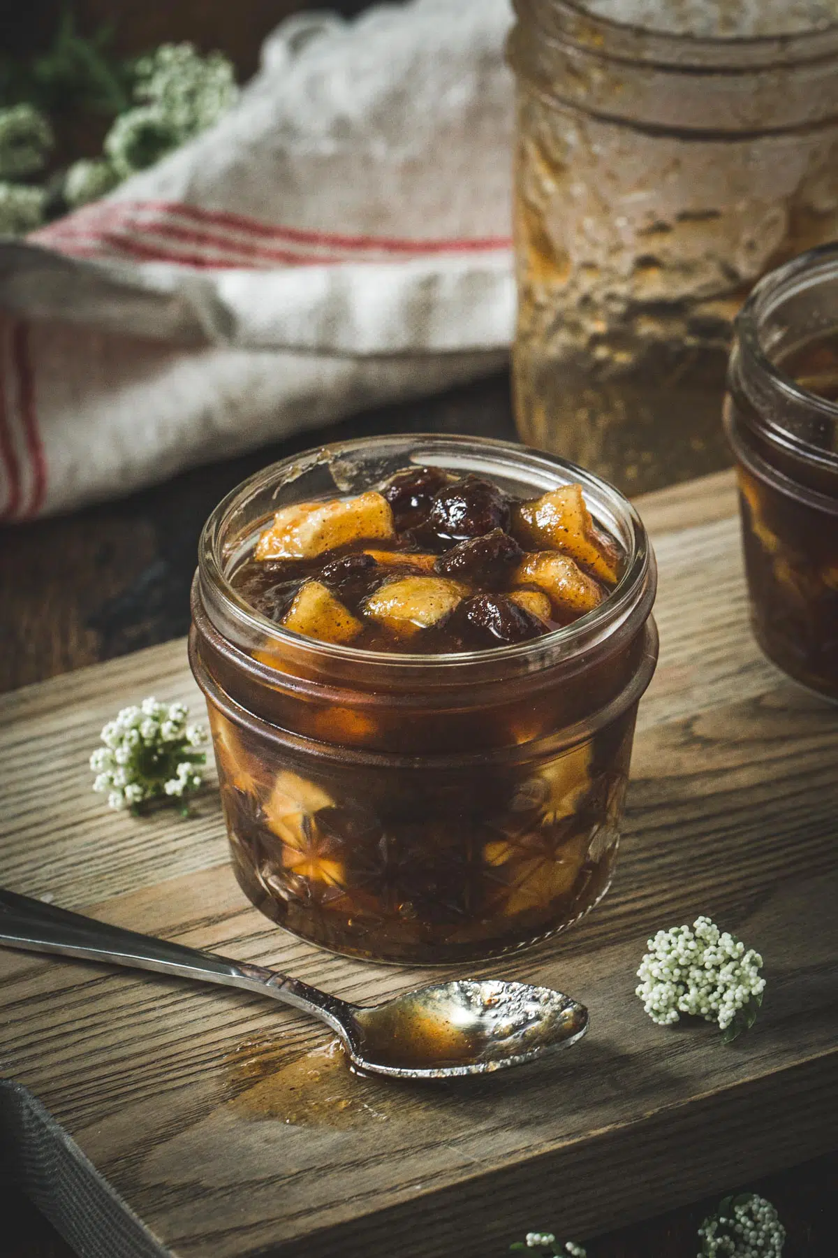 Dutch apple jam in a glass jar on a wooden cutting board.