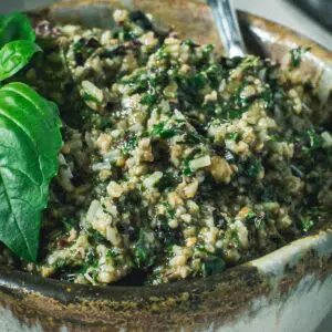 Beet greens pesto in a bowl with silver serving spoon.