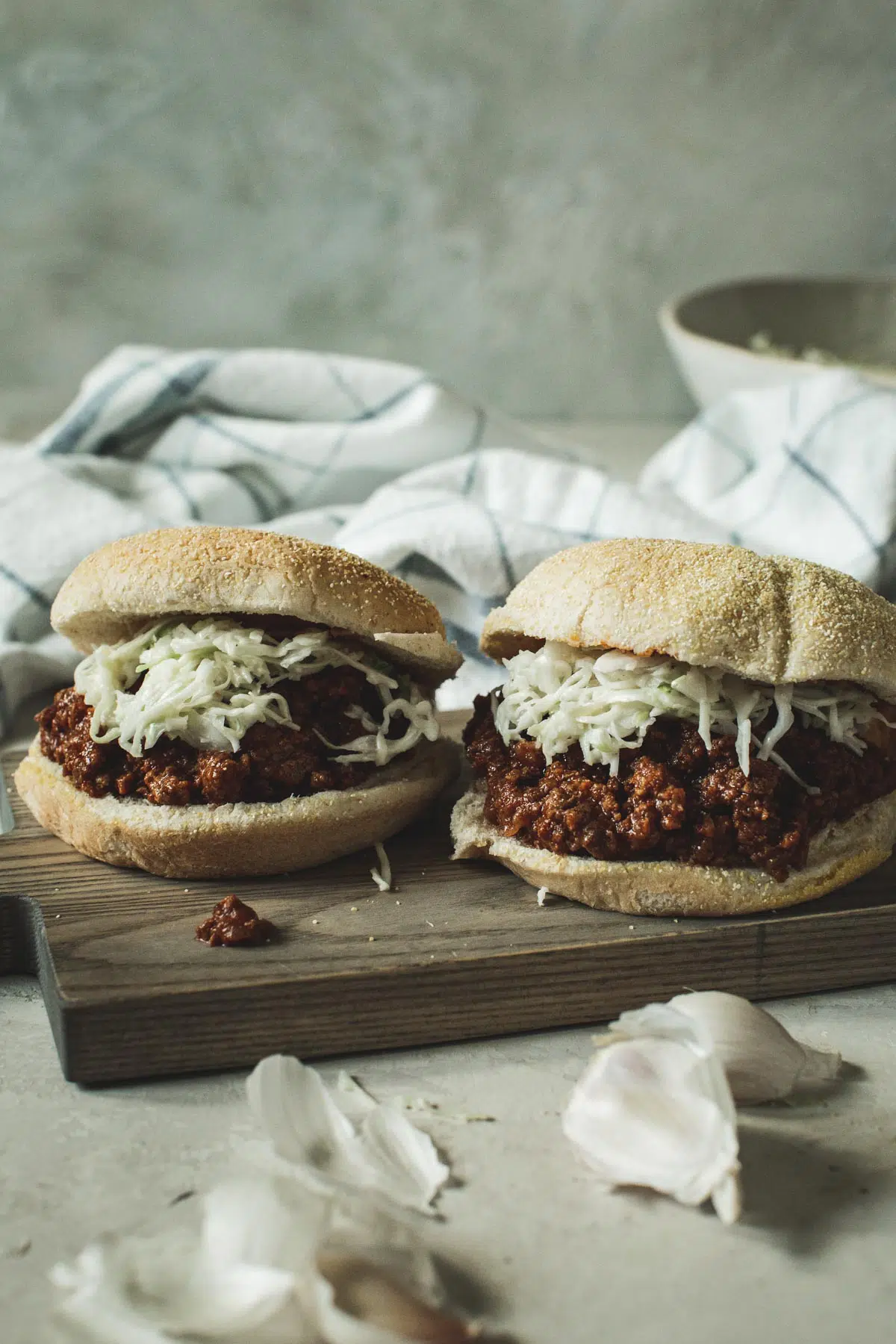 Sloppy Joes topped with coleslaw sitting on a wooden board.