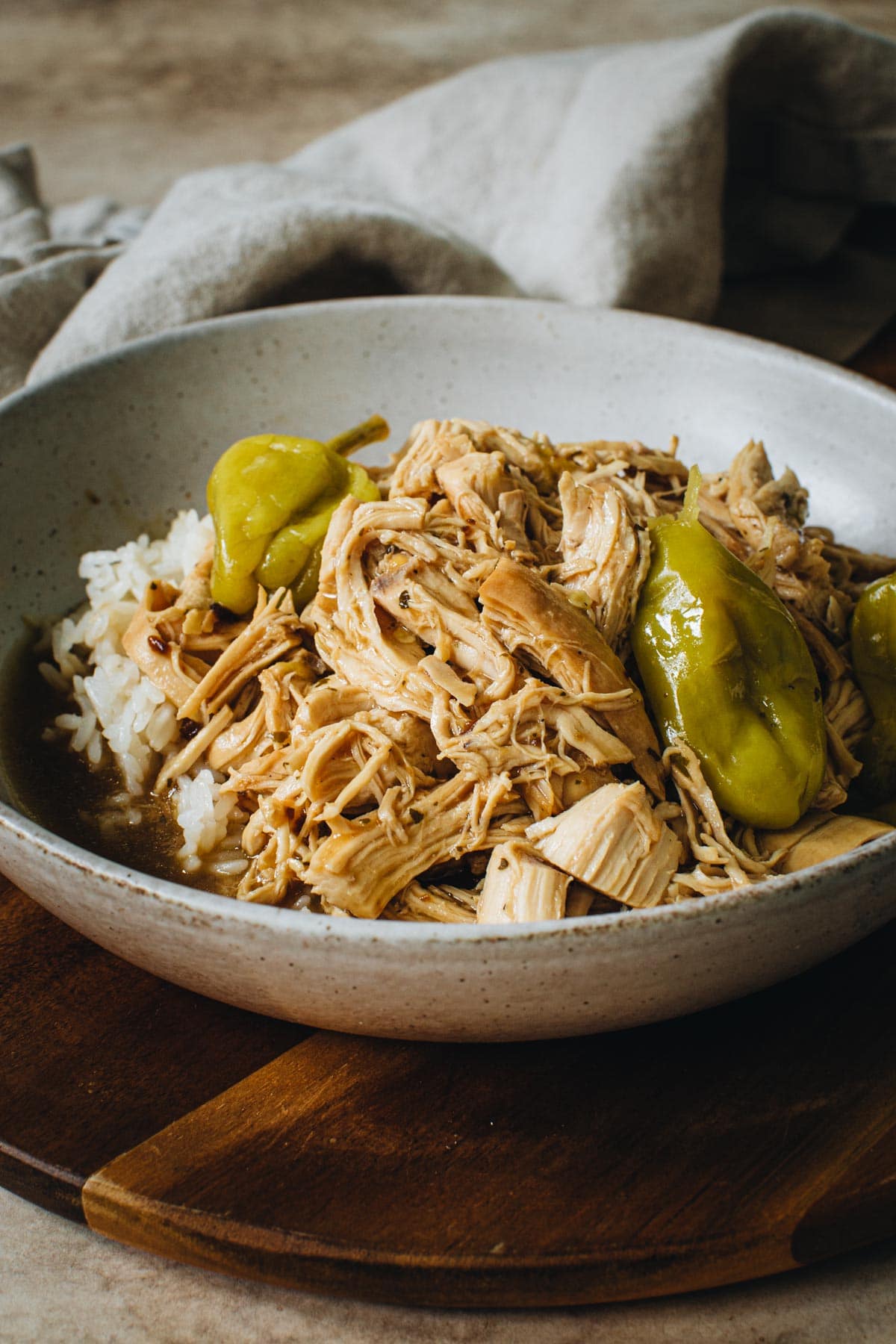 Mississippi chicken topped with pepperoncini peppers in a bowl.