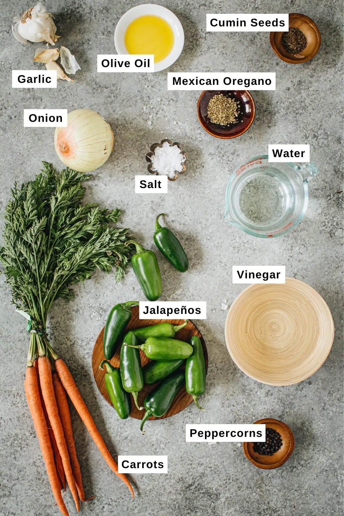 Pickled jalapeño and carrots ingredients in bowls on a table.