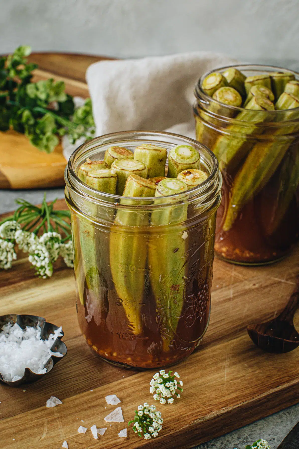 Pickled okra in a vinegar brine in a glass jar.