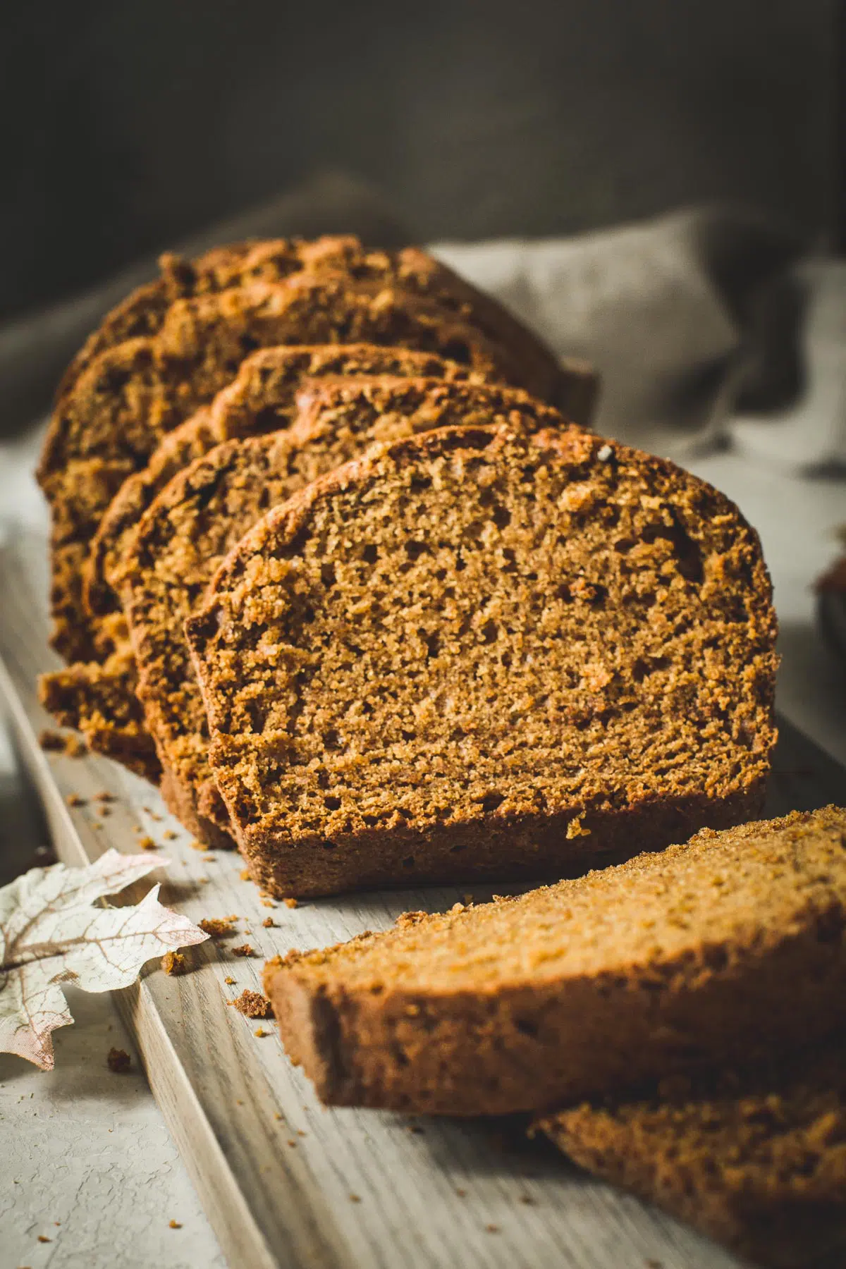 Pumpkin bread loaf sliced on a wooden cutting board.