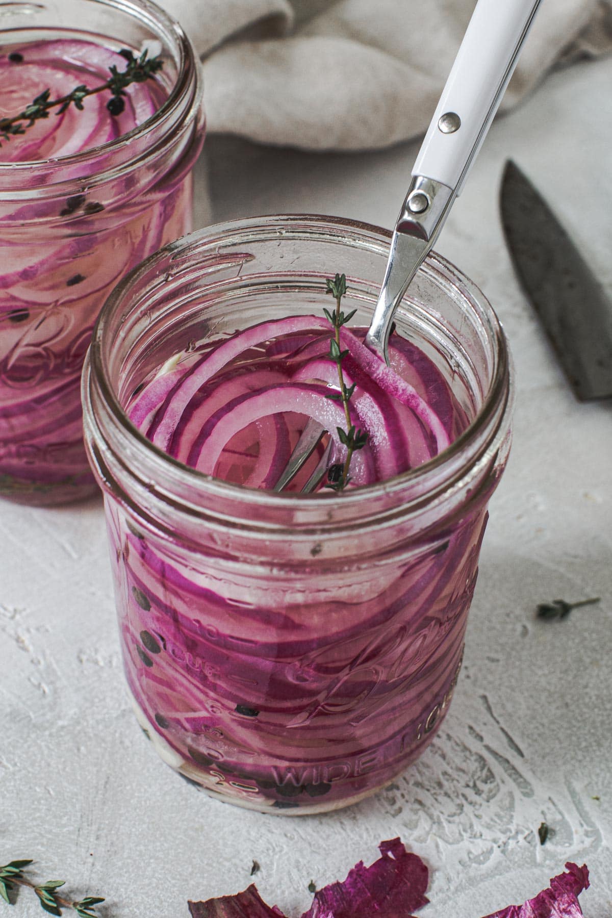 Quick pickled red onions in a pint jar with a white serving fork.