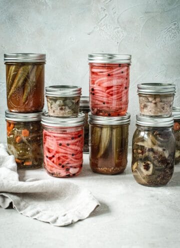 Cans of quick pickled vegetables in jars stacked on top of each other.
