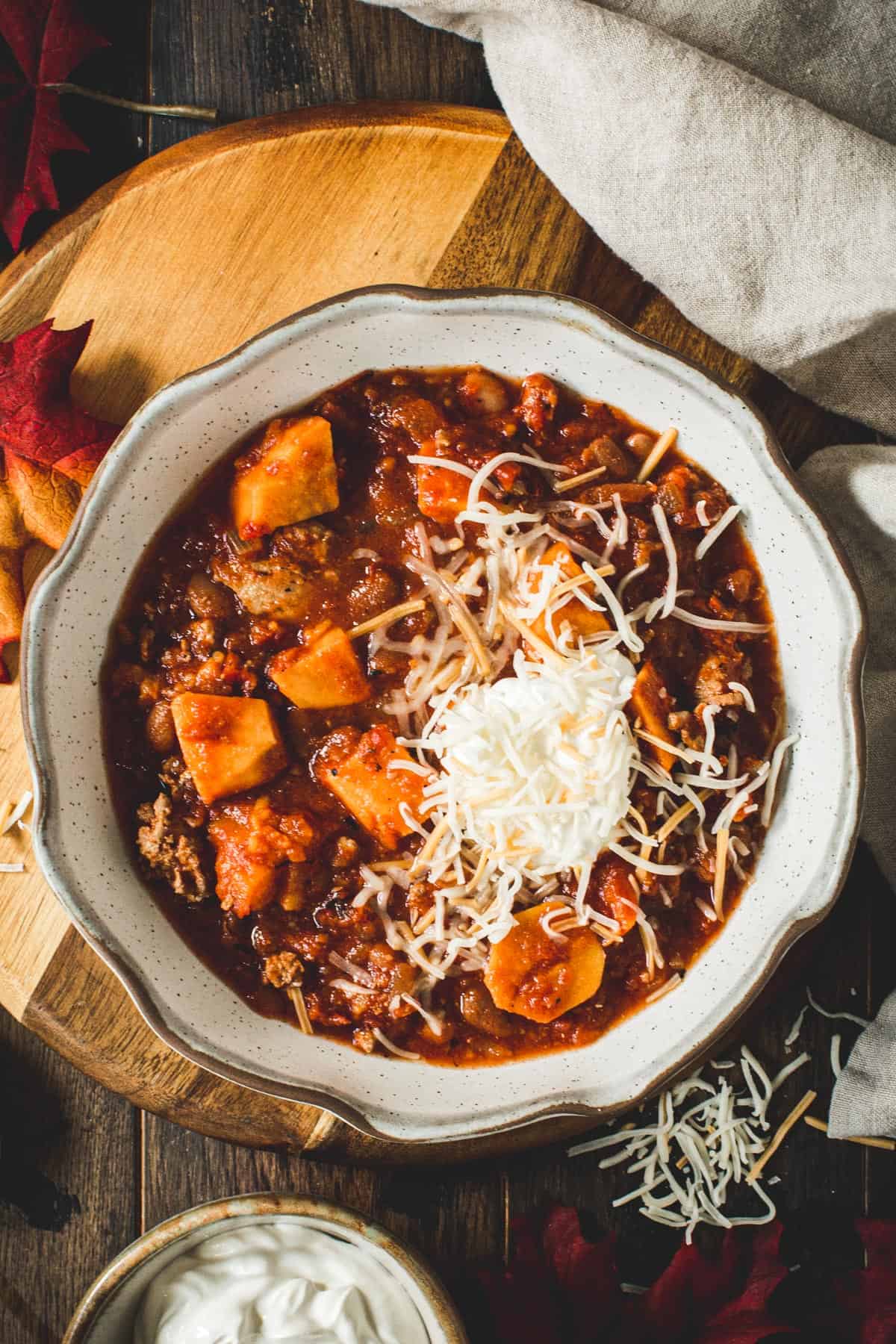 Crockpot sweet potato turkey chili topped with sour cream and shredded cheese.