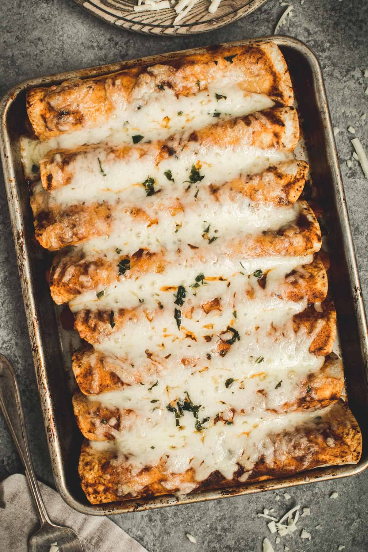 Butternut squash enchiladas on a rimmed baking sheet.