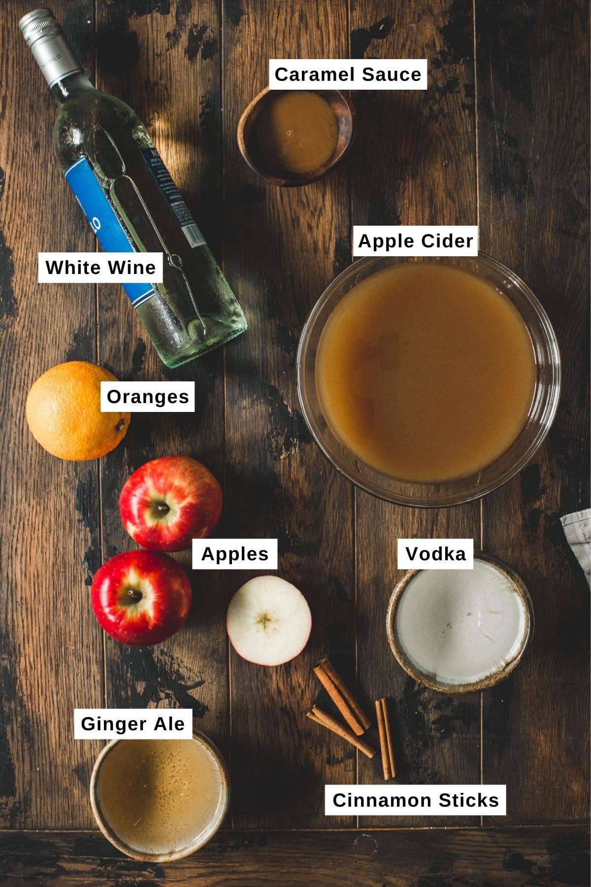 Caramel apple sangria ingredients on a wooden table.