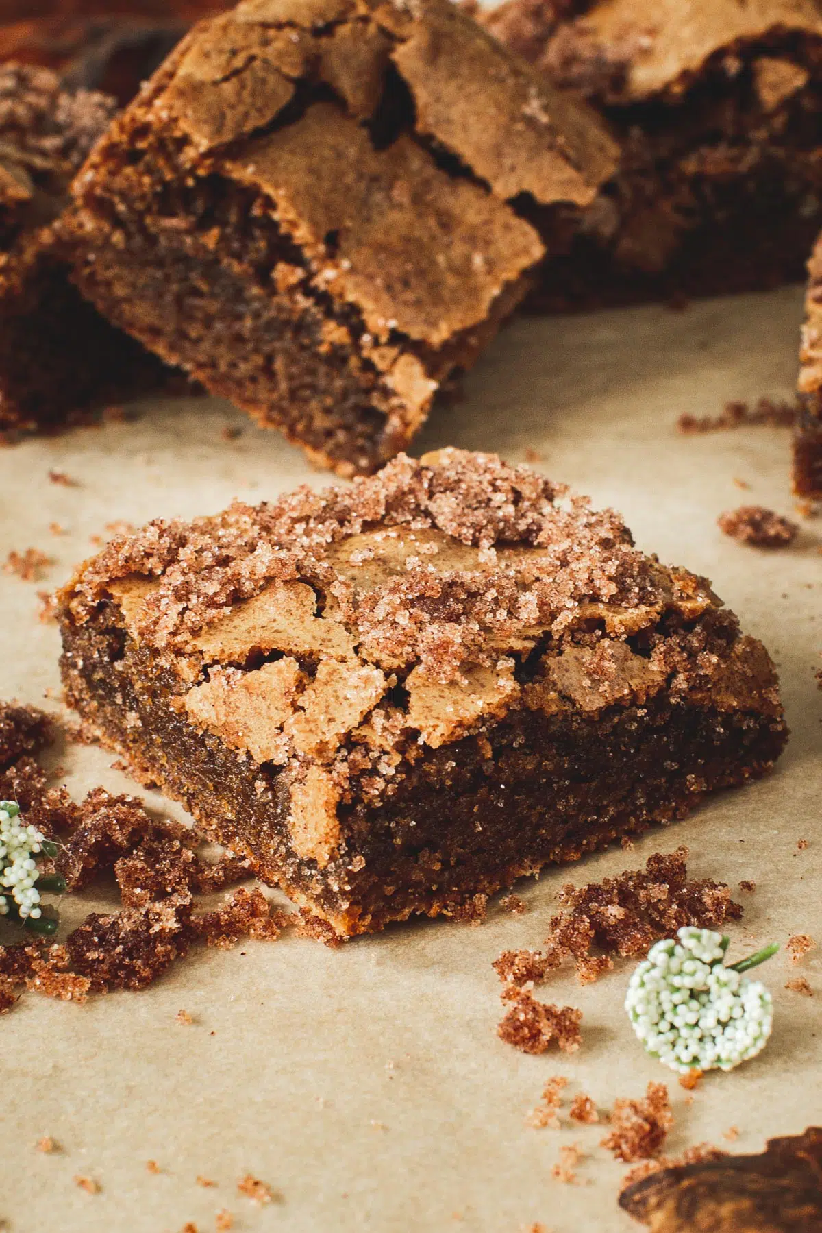 Cinnamon bar topped with a cinnamon sugar topping sitting on parchment paper.