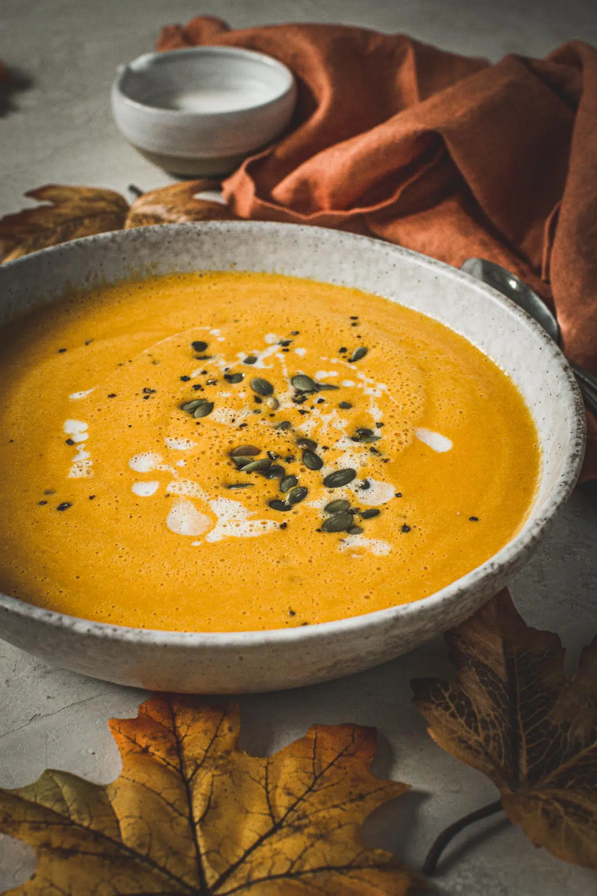 Curried pumpkin soup in a bowl topped with coconut milk and pumpkin seeds.