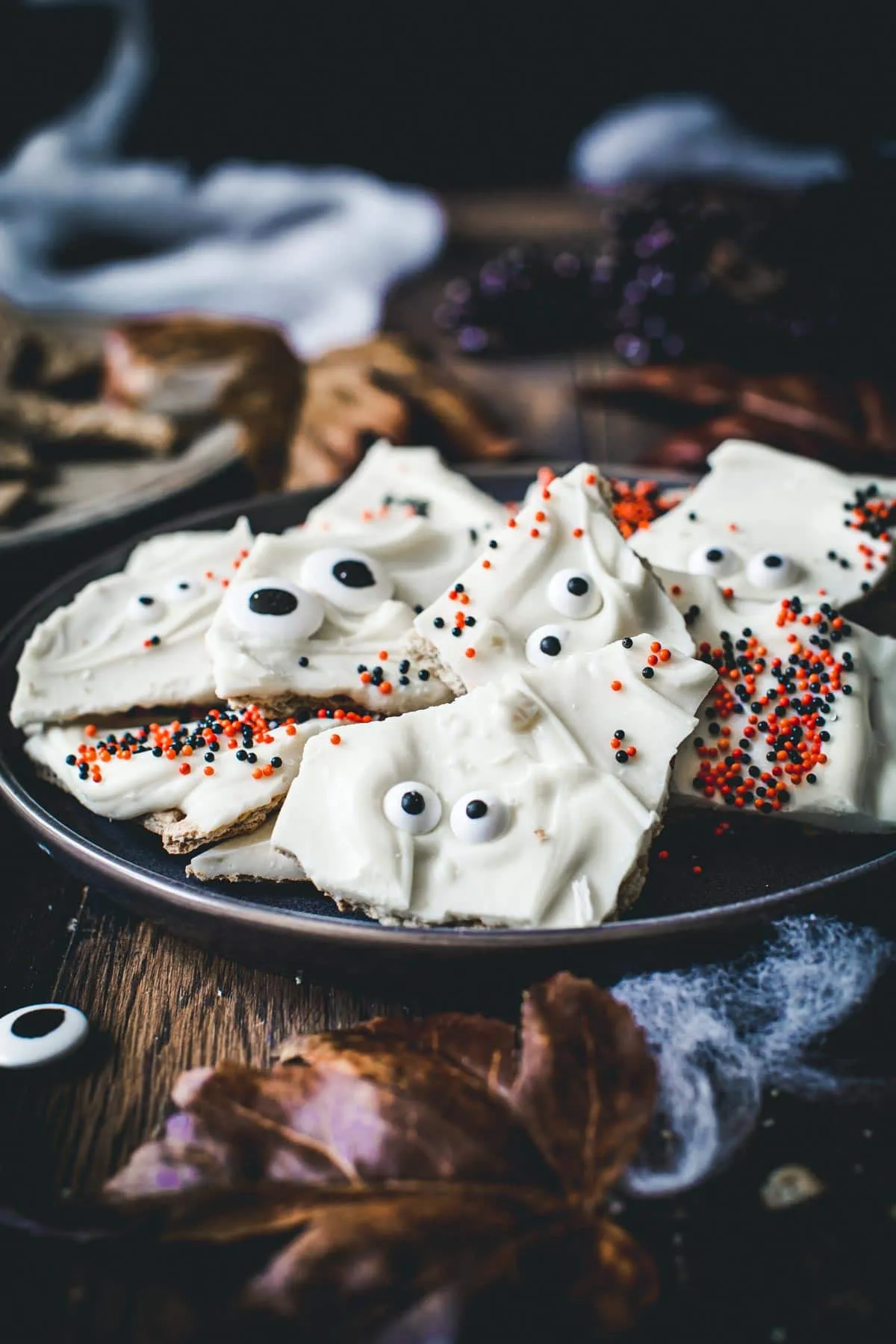 Halloween almond bark pieces on a black plate.