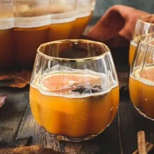 Pumpkin cocktail in a pumpkin-shaped glass with orange slices.