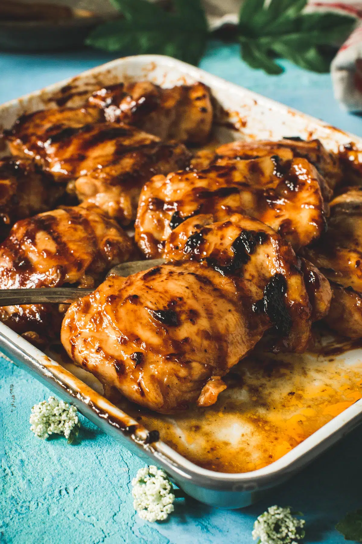 Huli huli chicken on a tray with a serving fork.