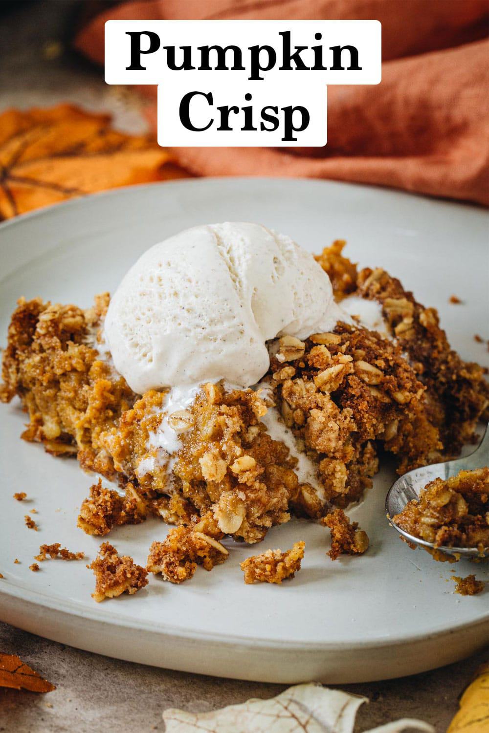 Pumpkin crisp covered in vanilla ice cream on a white plate.