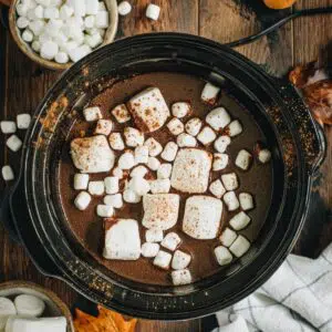 Pumpkin hot chocolate in a slow cooker topped with marshmallows.