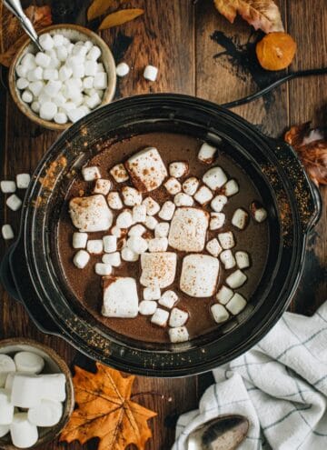 Pumpkin hot chocolate in a slow cooker topped with marshmallows.