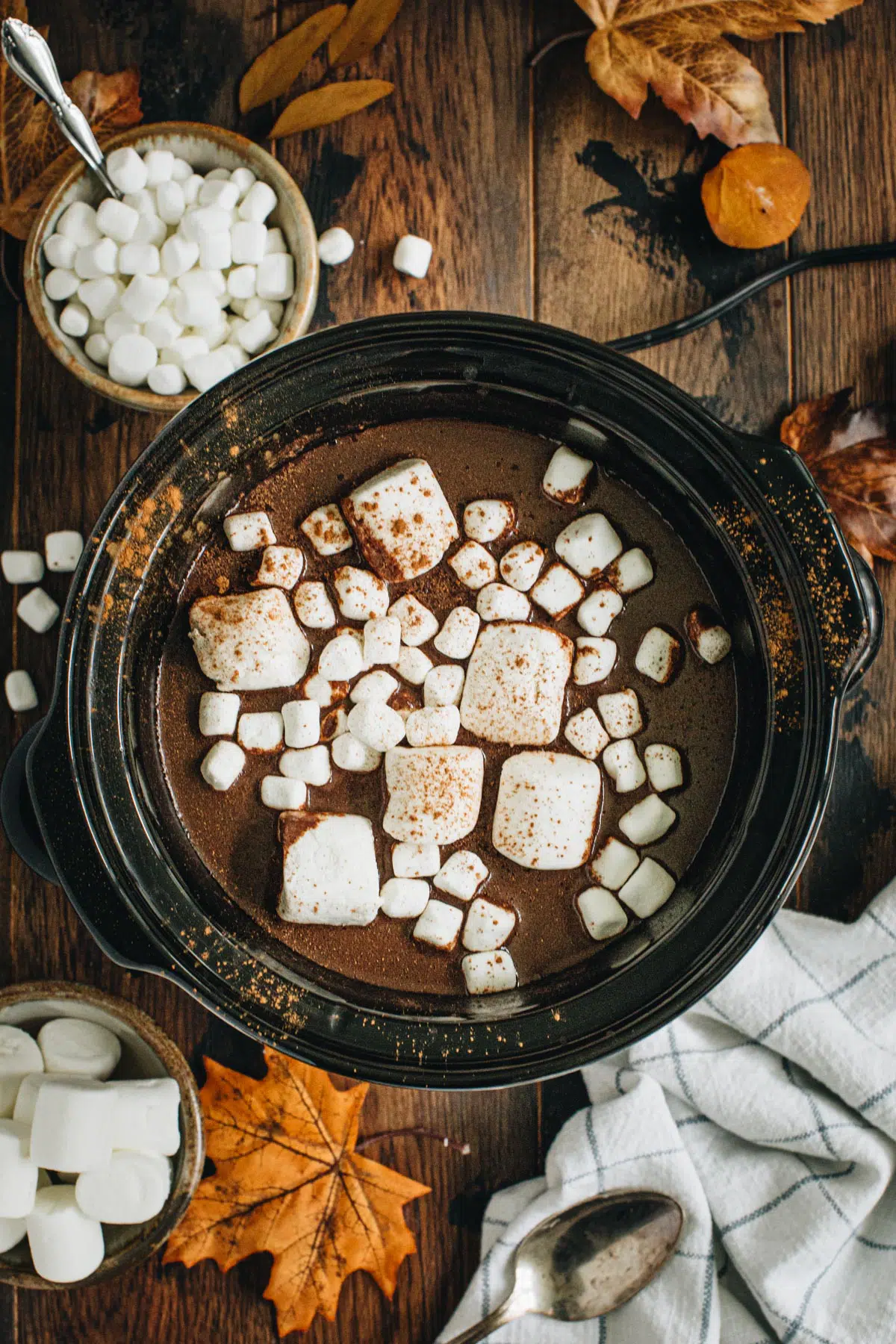Pumpkin hot chocolate in a slow cooker topped with marshmallows.