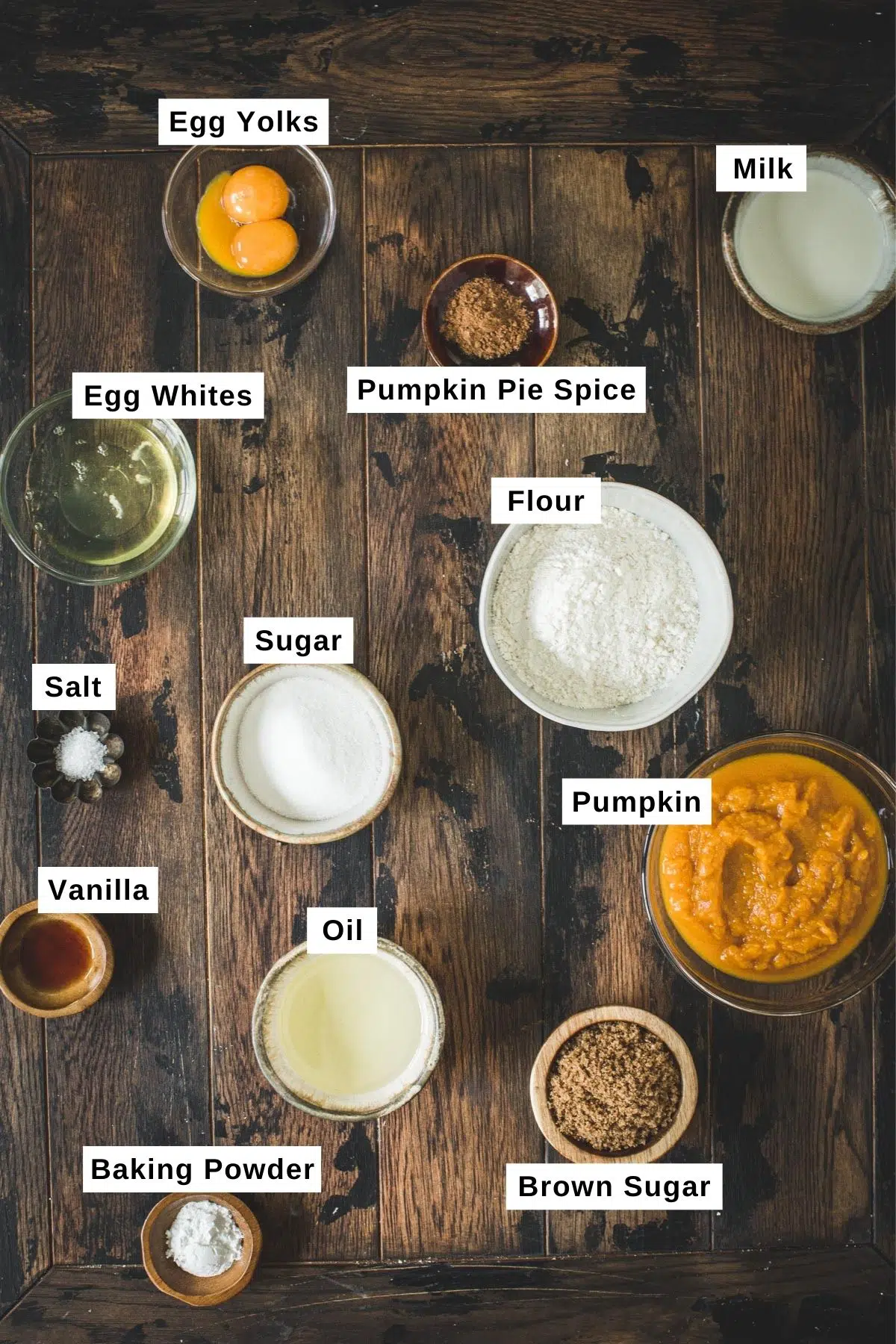 Pumpkin spice waffles ingredients in bowls on a wooden table.