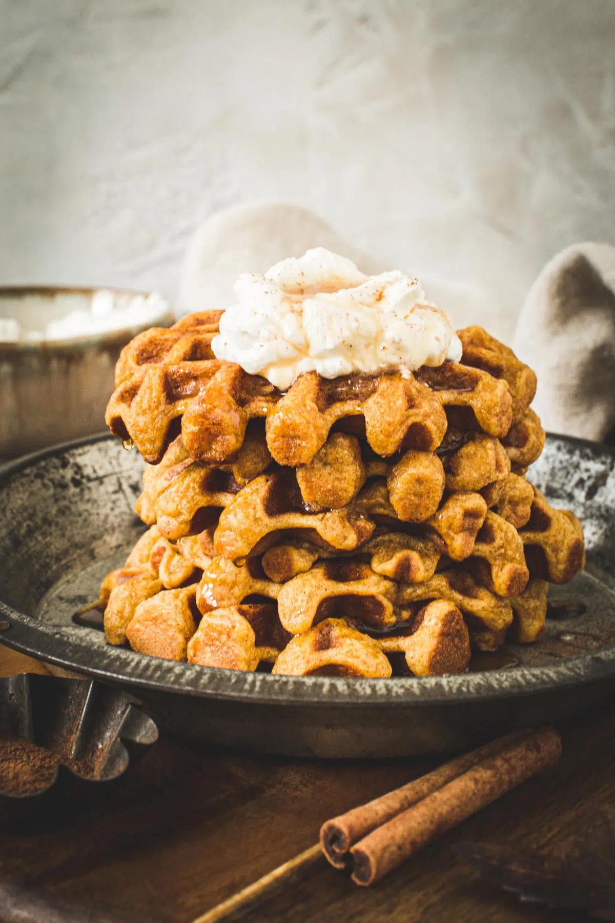 Stack of pumpkin spice waffles with whipped cream on top.