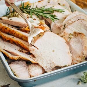 Oven-roasted turkey breast with a serving fork holding up a peice.