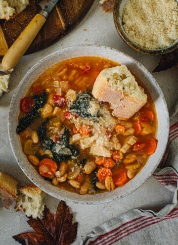 Tuscan white bean soup in a bowl with crusty bread on top.