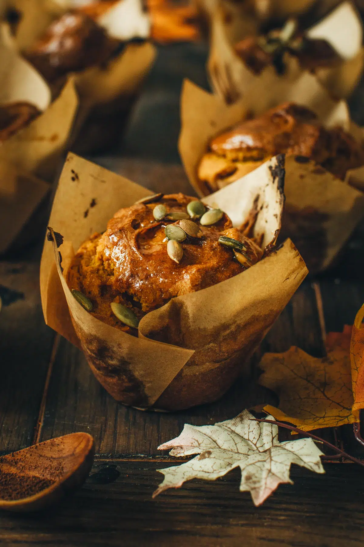 Vegan pumpkin muffin topped with pumpkin seeds in a paper liner.