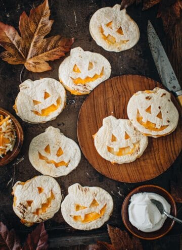 Jack-O-Lantern quesadillas on a wooden plate.