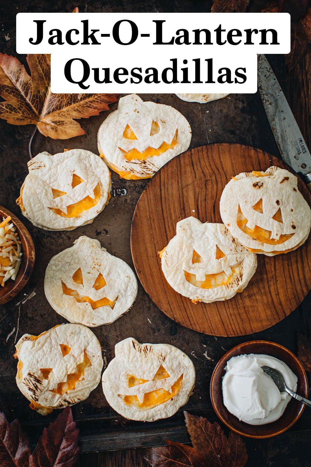 Jack-o-lantern quesadillas on a baking sheet and wooden plate.