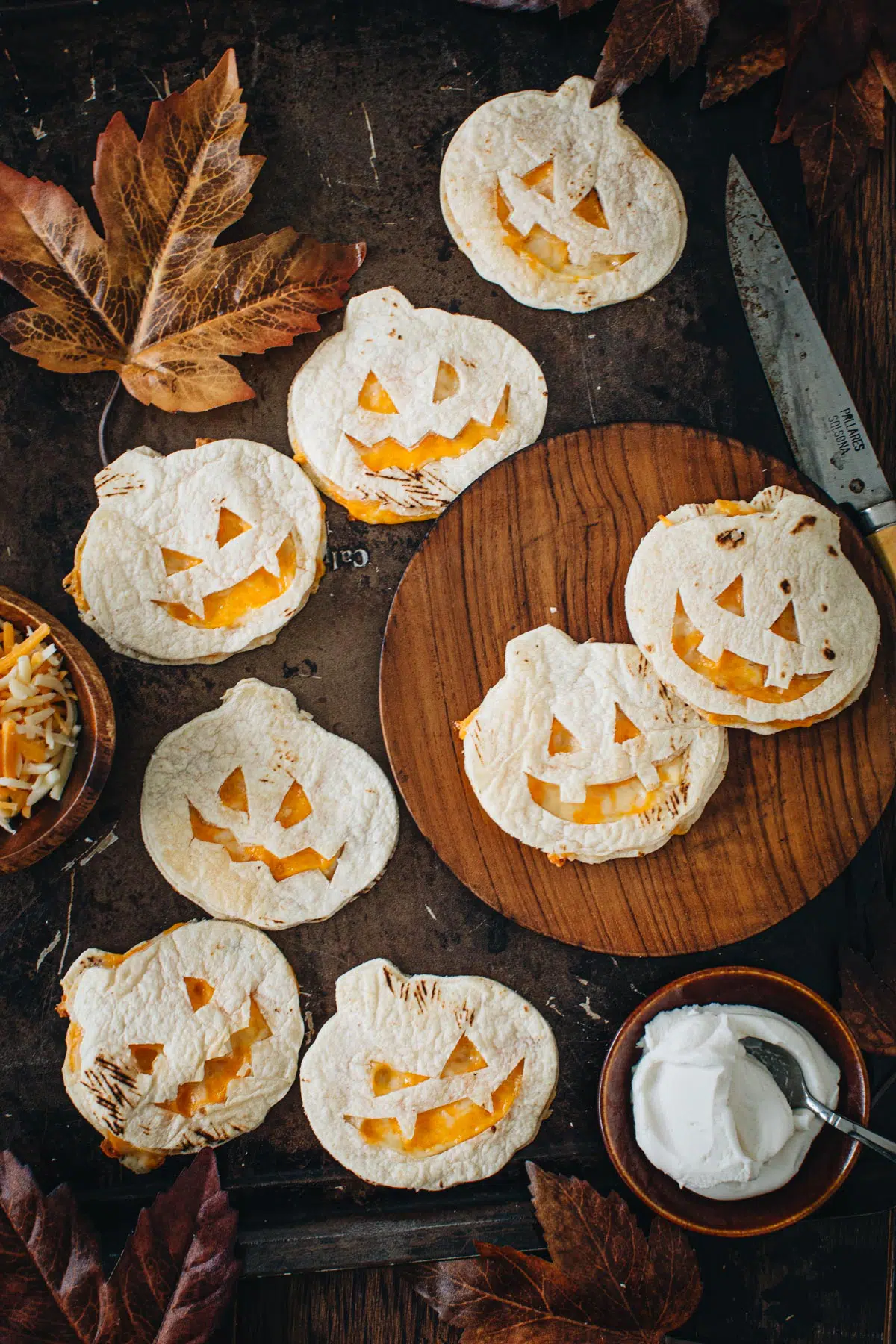 Jack-O-Lantern quesadillas on a wooden plate.