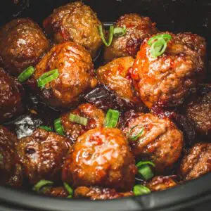 Party meatballs in the Crockpot covered with green onions.