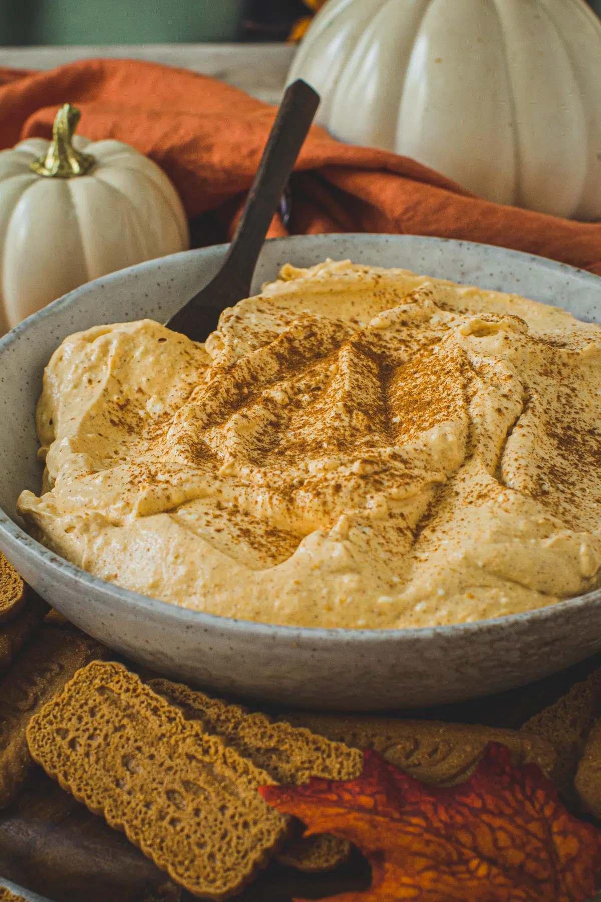 Pumpkin cheesecake dip topped with cinnamon and in a bowl.