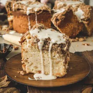 Slice of apple crumb cake on a wooden plate.