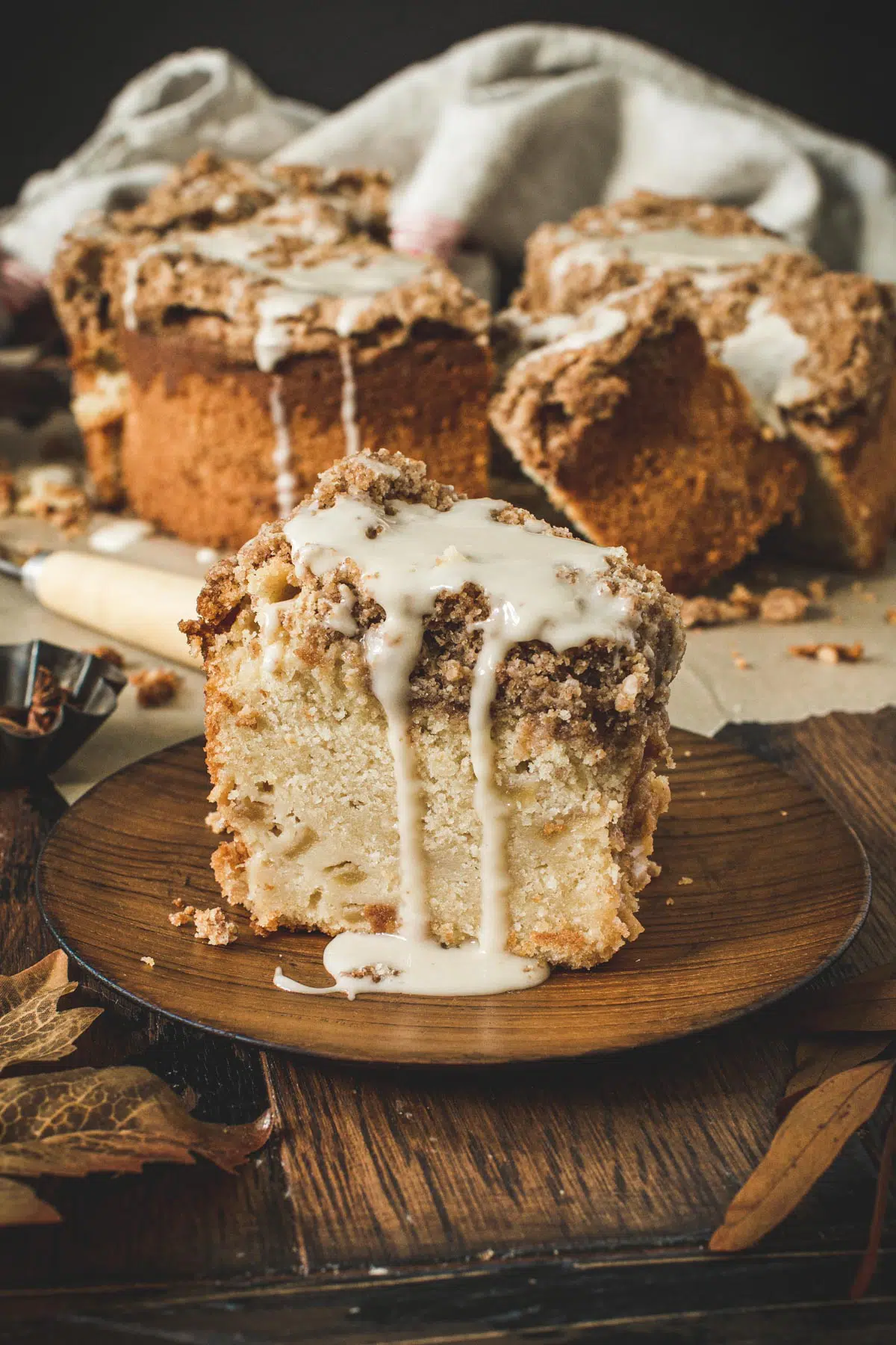 Slice of apple crumb cake on a wooden plate.