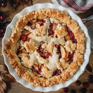 Apple cranberry pie in a white pie dish.