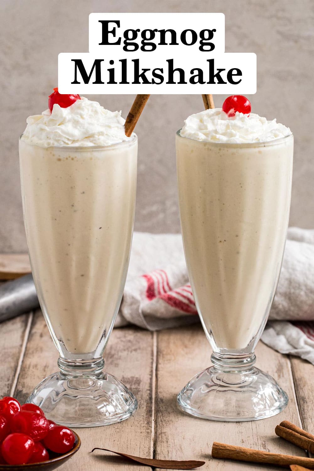 Eggnog milkshakes in glasses topped with whipped cream and cherries.