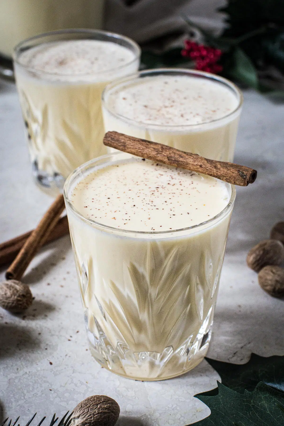 Homemade eggnog in a glass topped with fresh nutmeg and a cinnamon stick.