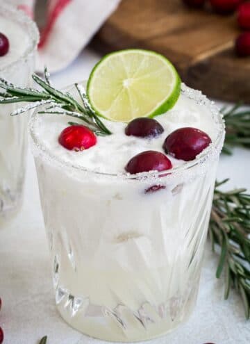White Christmas margarita topped with fresh cranberries and a lime slice.